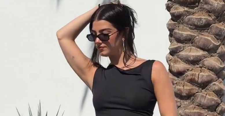 Charli poses by the pool in a cream dress and sunglasses, establishing the aspirational opening hook.
![YouTube video poster